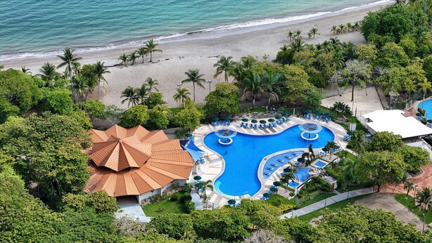 A resort with a large swimming pool, beach access, and lush greenery. - Hotel Punta Leona (Tárcoles)