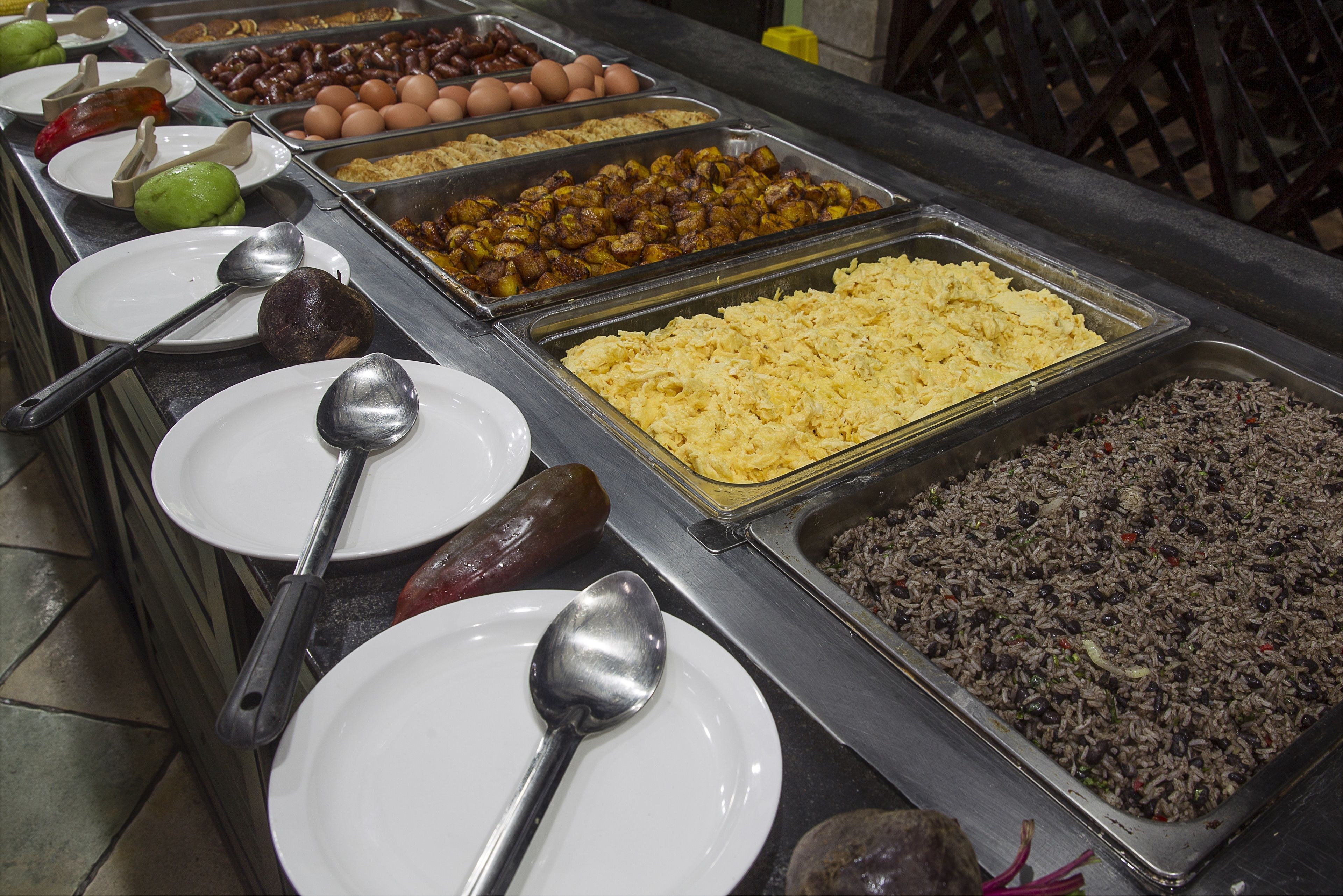 A buffet with various food options including meats, eggs, and rice.