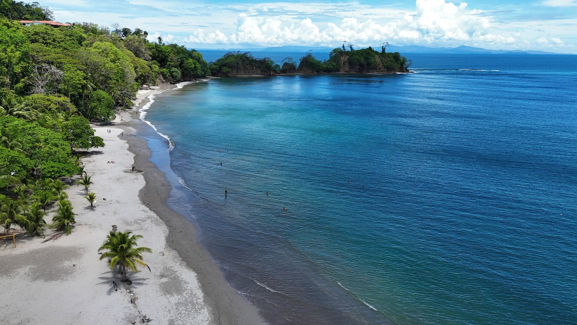 Une plage aux eaux turquoise et limpides, bordée d’un rivage sablonneux et d’une végétation luxuriante.