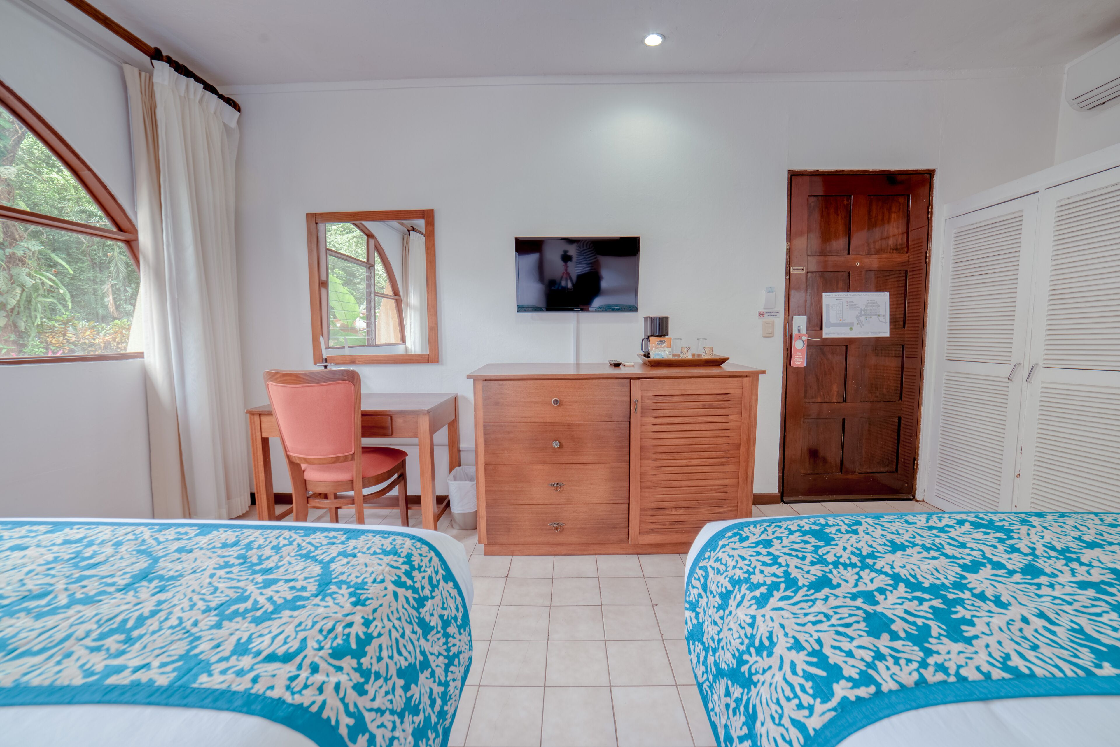 A bedroom with two beds, a desk, a chair, a television, and a wardrobe.