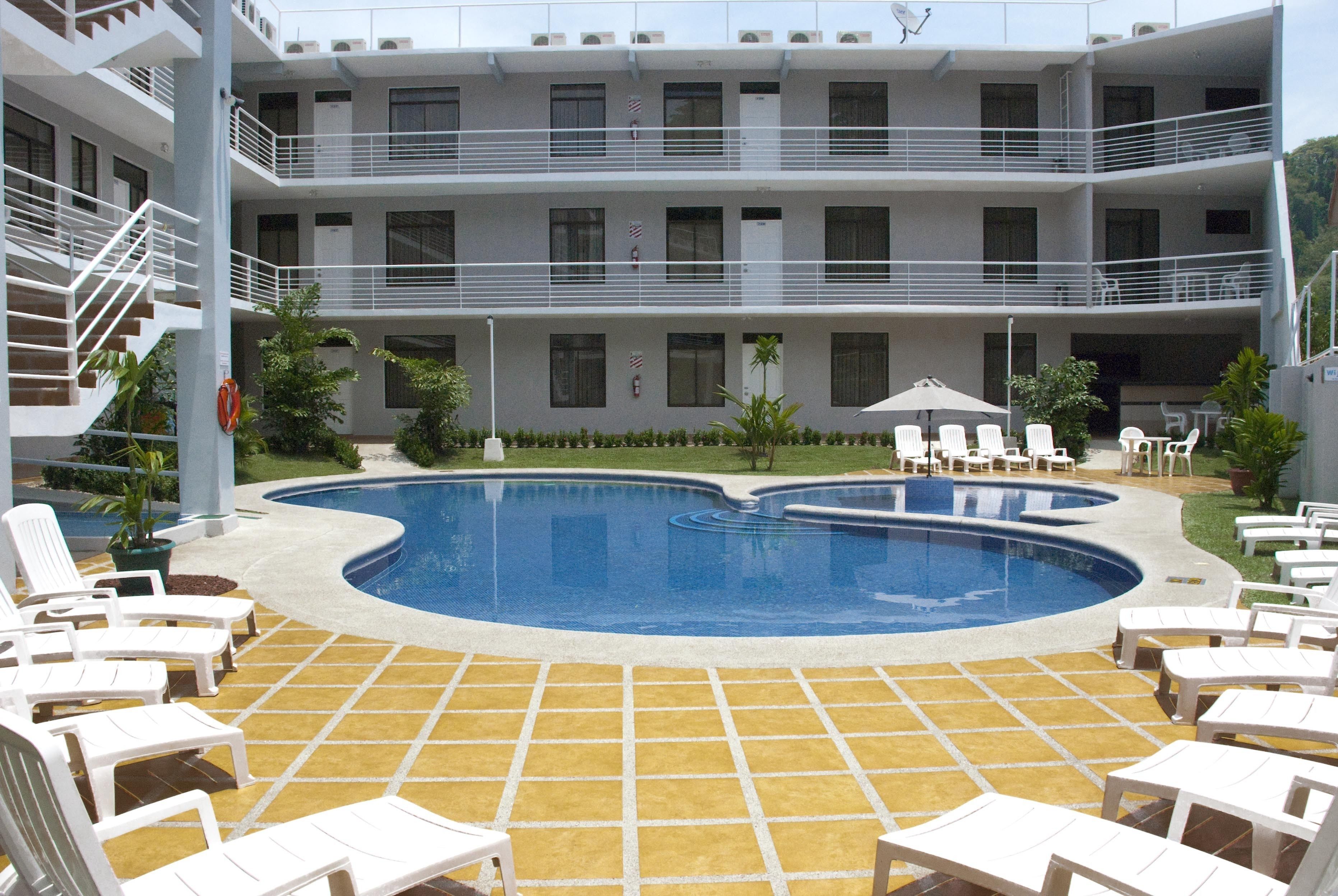 A hotel pool area with multiple levels, outdoor seating, and a clear view of the pool.