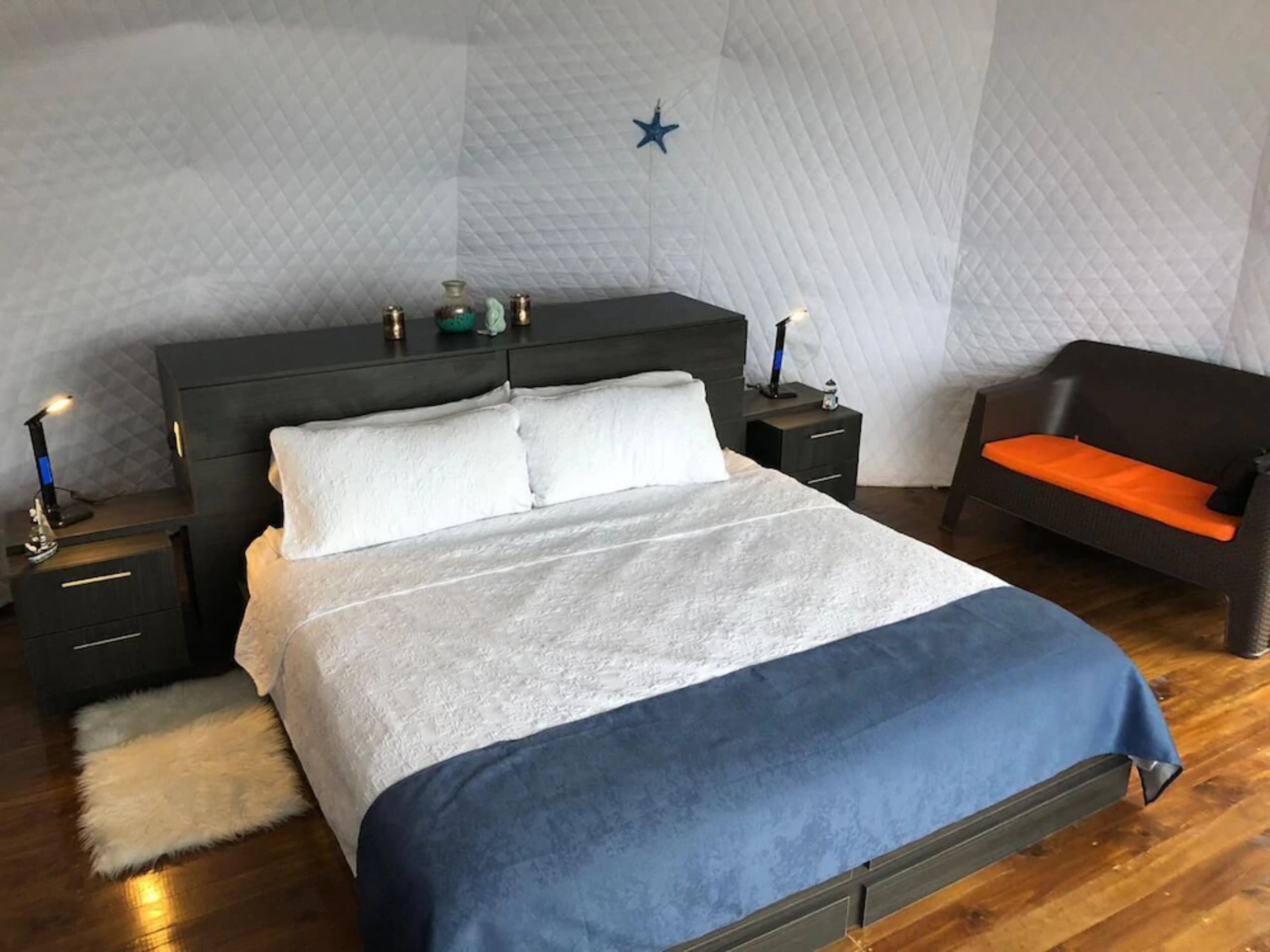 A bedroom with a bed, bedside tables, a nightstand, a chair, and a star decoration on the wall.