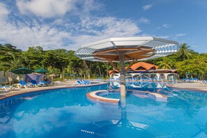 Una piscina con agua azul, rodeada de sillas de descanso y sombrillas.