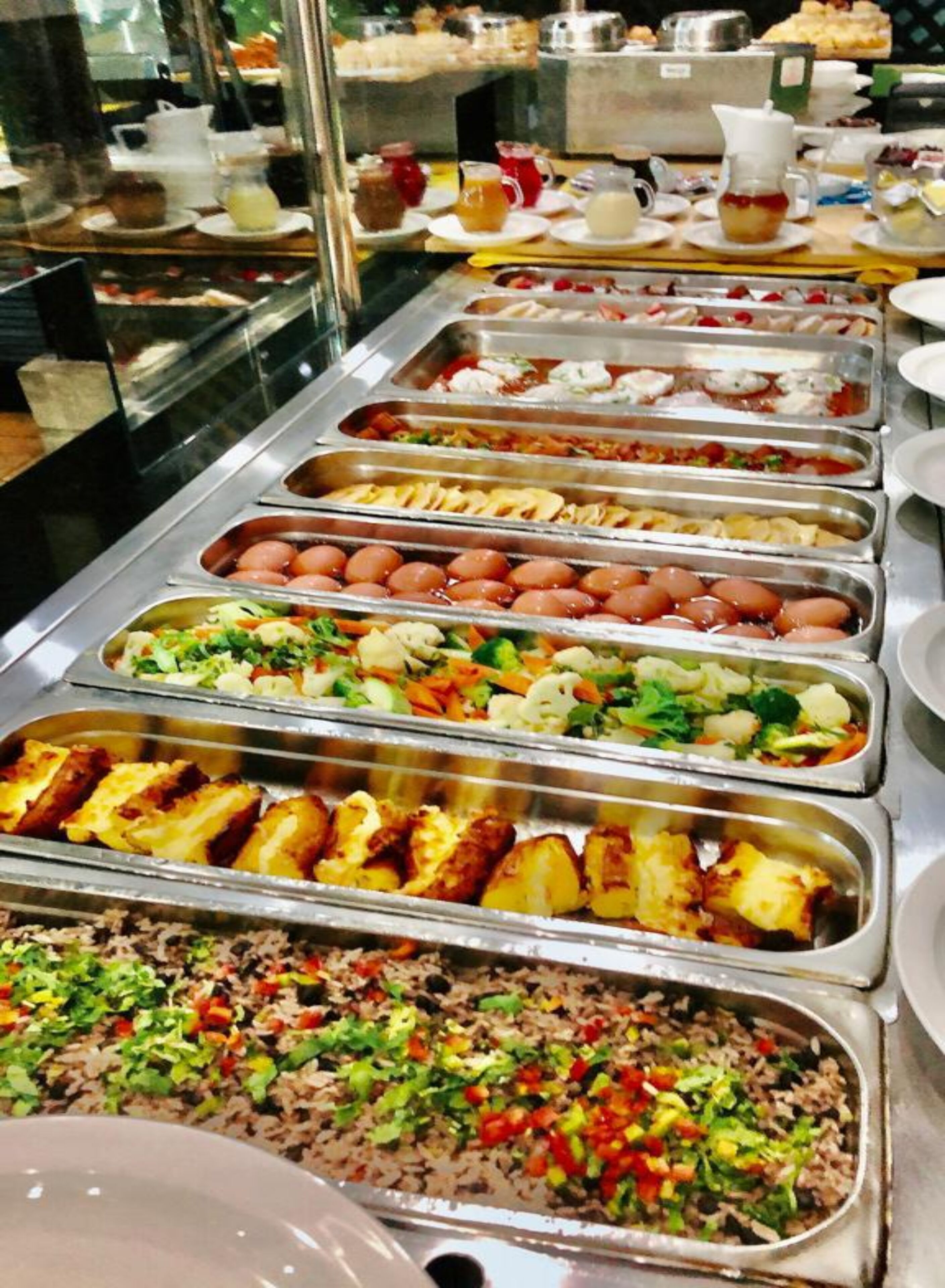 Ein Buffet mit verschiedenen Speisen, darunter Salate, Fleischgerichte und Reis.