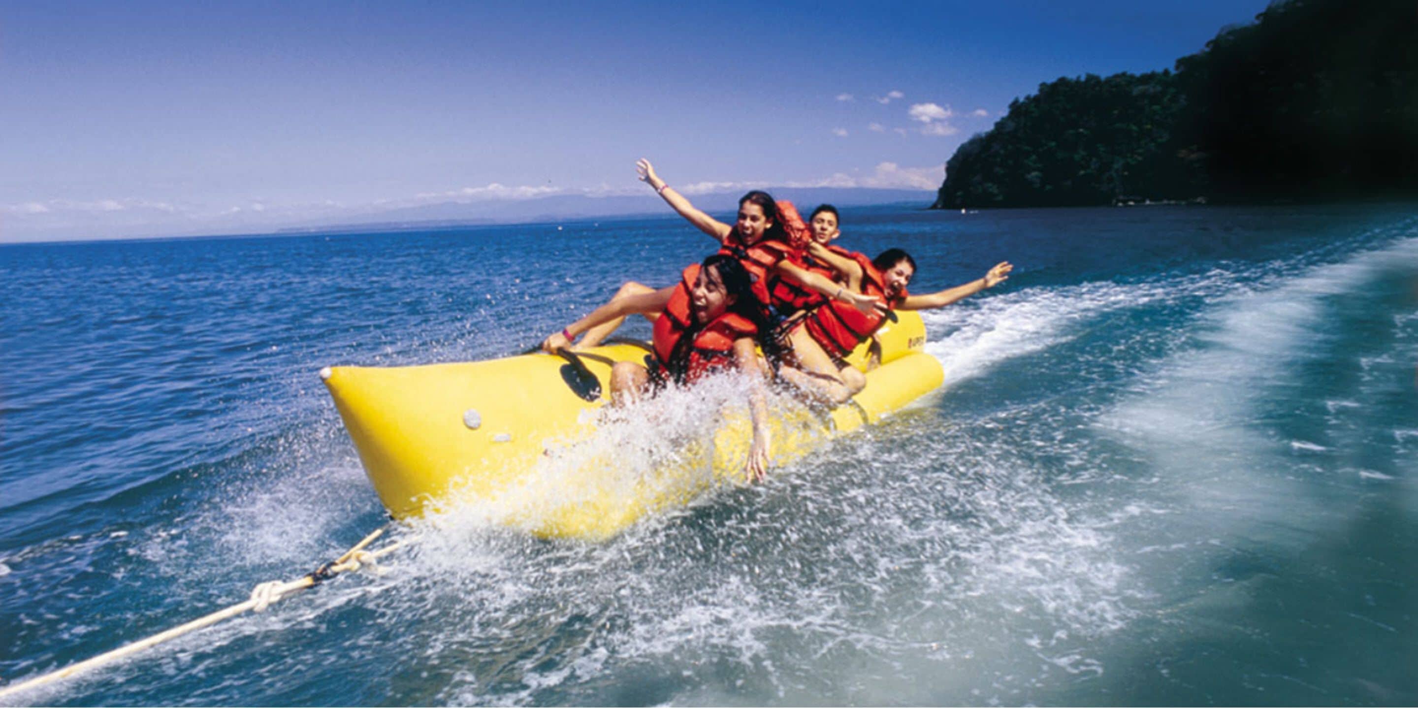 Un grupo de personas en un bote amarillo con chalecos salvavidas, flotando en el agua.