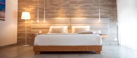 A modern bedroom with a large bed, wooden headboard, and pendant lights.