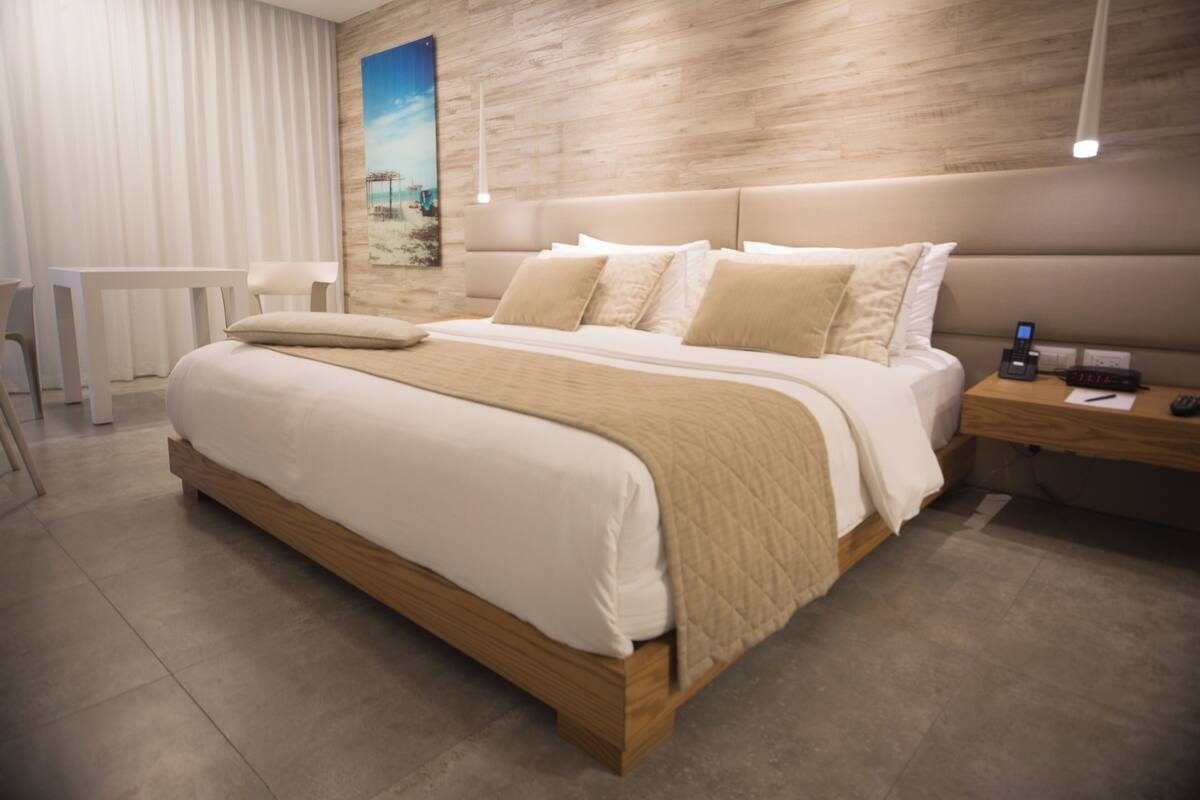 Un dormitorio moderno con una cama grande, una mesita de noche con un teléfono y un cuadro en la pared.