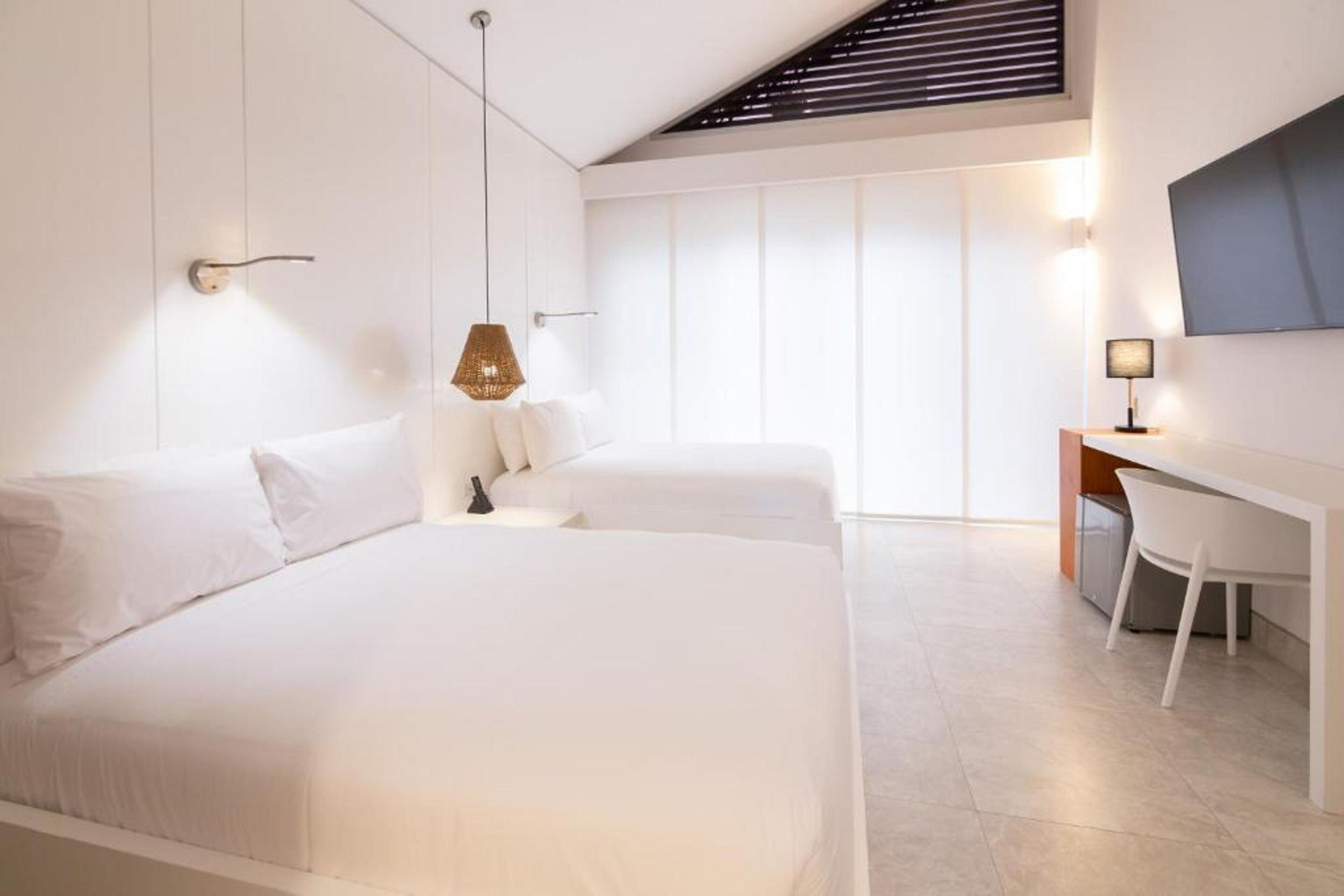 A modern hotel room with a large bed, a desk, and a TV mounted on the wall.