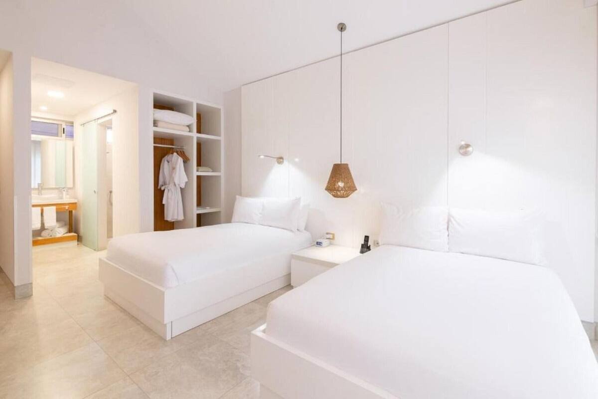 Una habitación de hotel moderna con dos camas, un vestidor y un baño.
