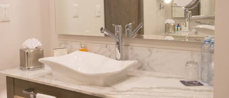 A bathroom with a marble sink, a large mirror, and a towel rack with towels.