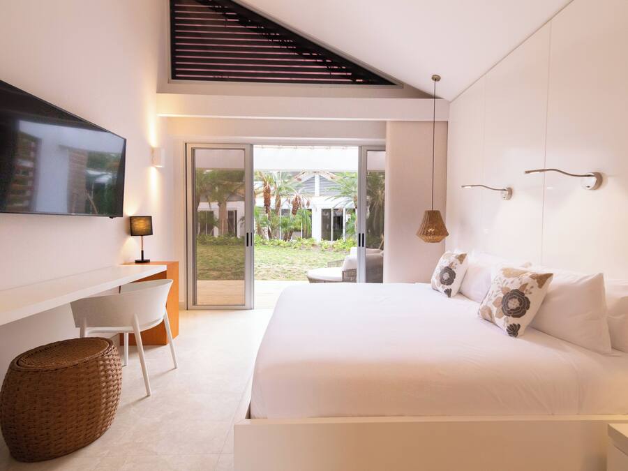A modern hotel room with a bed, a desk, a television, and a view of the outdoors.