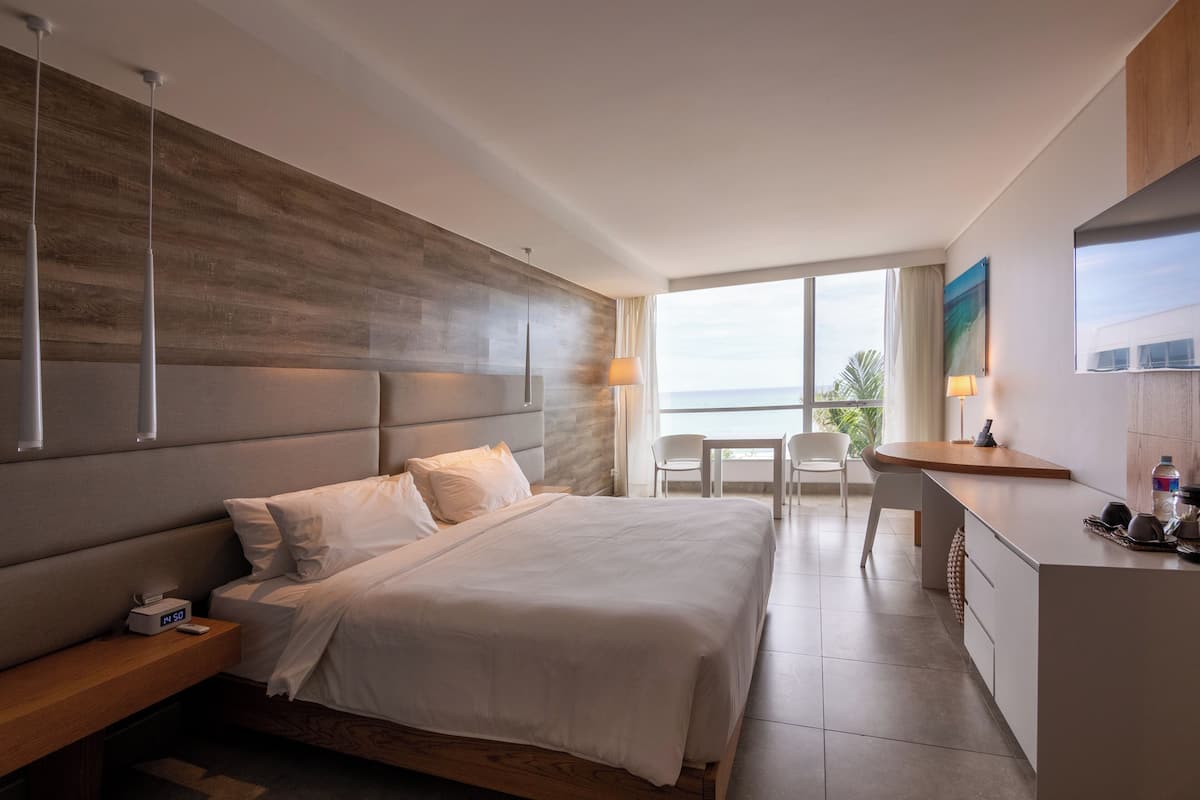 Habitación de hotel moderna con una cama grande, un escritorio y vistas al exterior.