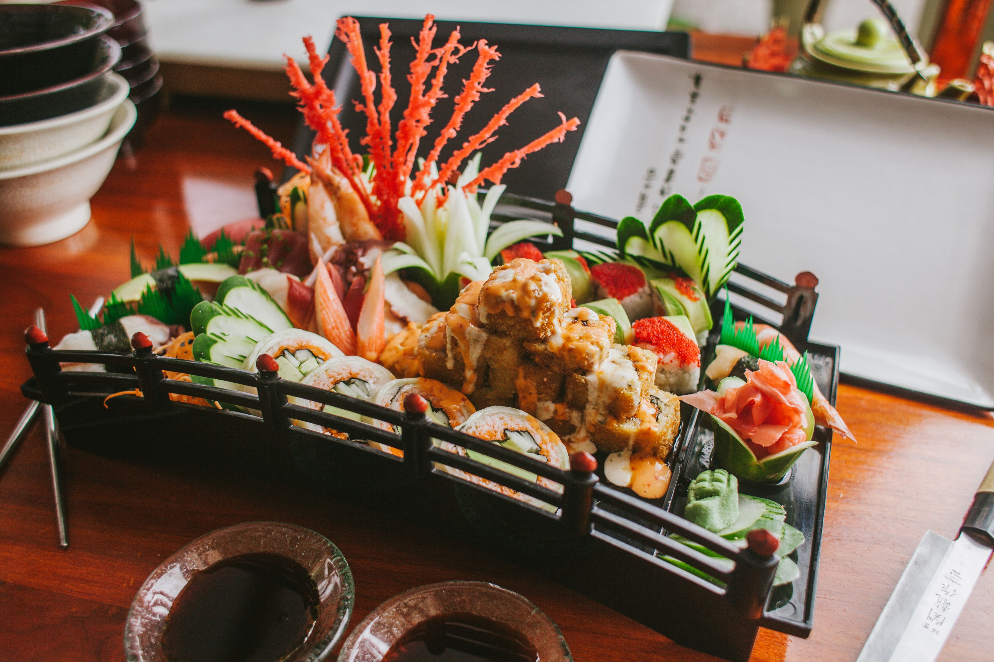 Una bandeja de sushi con distintos tipos de sushi y guarniciones sobre una mesa de madera.