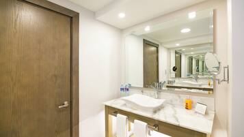 A modern bathroom with a wooden door, a large mirror, a marble sink, and a towel rack.