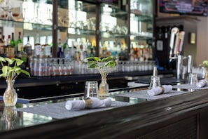 A bar area with a glass counter, vases with plants, and various bottles in the background. - SEVEN Sebring Raceway Hotel (Sebring)