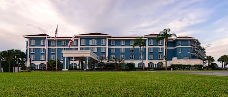 Un hotel grande de varios pisos con una fachada simétrica, múltiples balcones y un césped bien cuidado al frente.