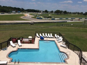 A pool area with lounge chairs and a 'No Diving' sign, surrounded by a fenced track.