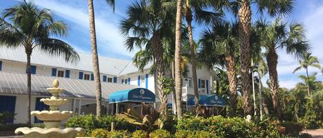 A hotel courtyard with a fountain, palm trees, and a registration tent.