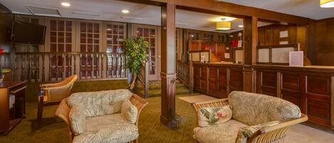 A lobby with wicker furniture, a reception desk, and wooden paneling.