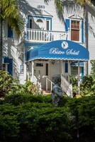 Un edificio blanco con contraventanas azules y un toldo azul que dice 'Bistro Soleil'.