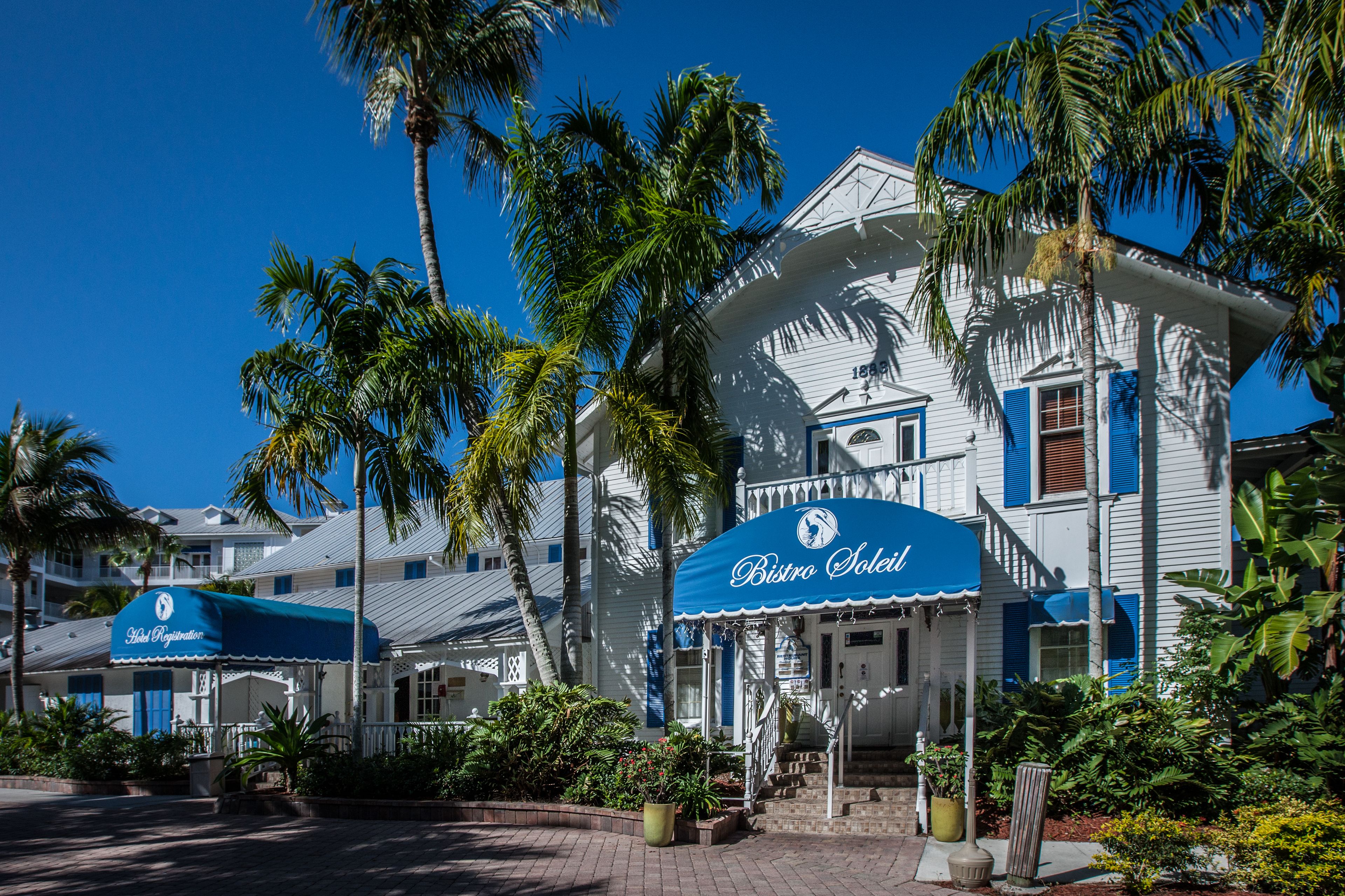 A white building with a blue awning labeled "Bistro Soleil."