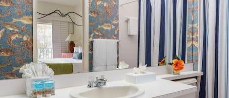 Une salle de bain avec un lavabo blanc, un miroir et un rideau de douche à rayures bleues et blanches.