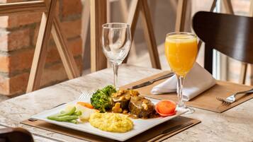 A table set with a meal, a glass of orange juice, and a wine glass.