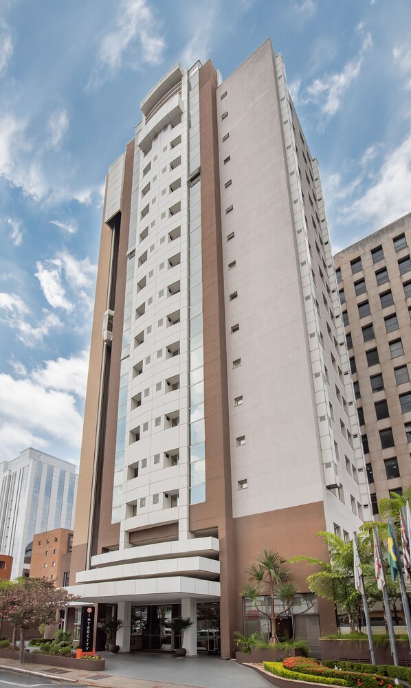 Un hotel alto y moderno con una entrada destacada y un cielo despejado.