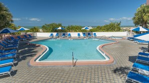 Una piscina al aire libre, sombrillas, sillones reclinables de piscina