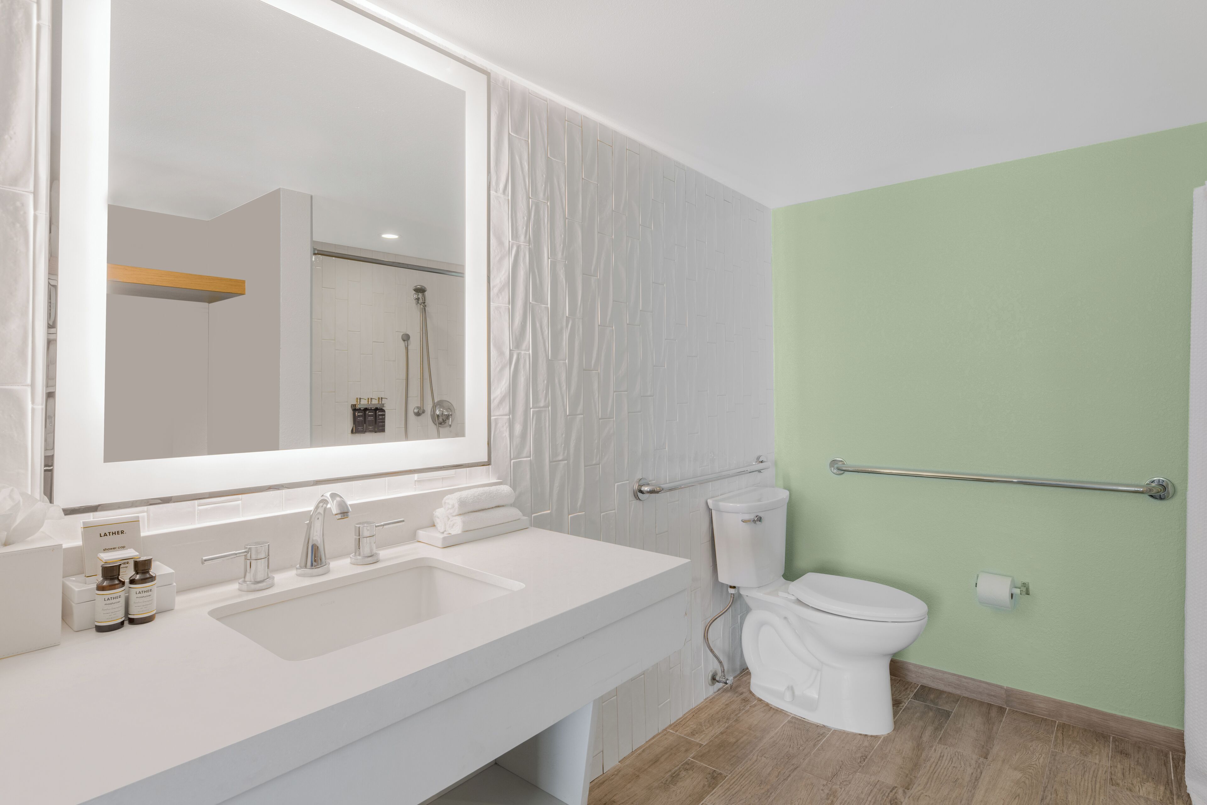 A modern bathroom with a white sink, a large mirror, a toilet, and a shower area.