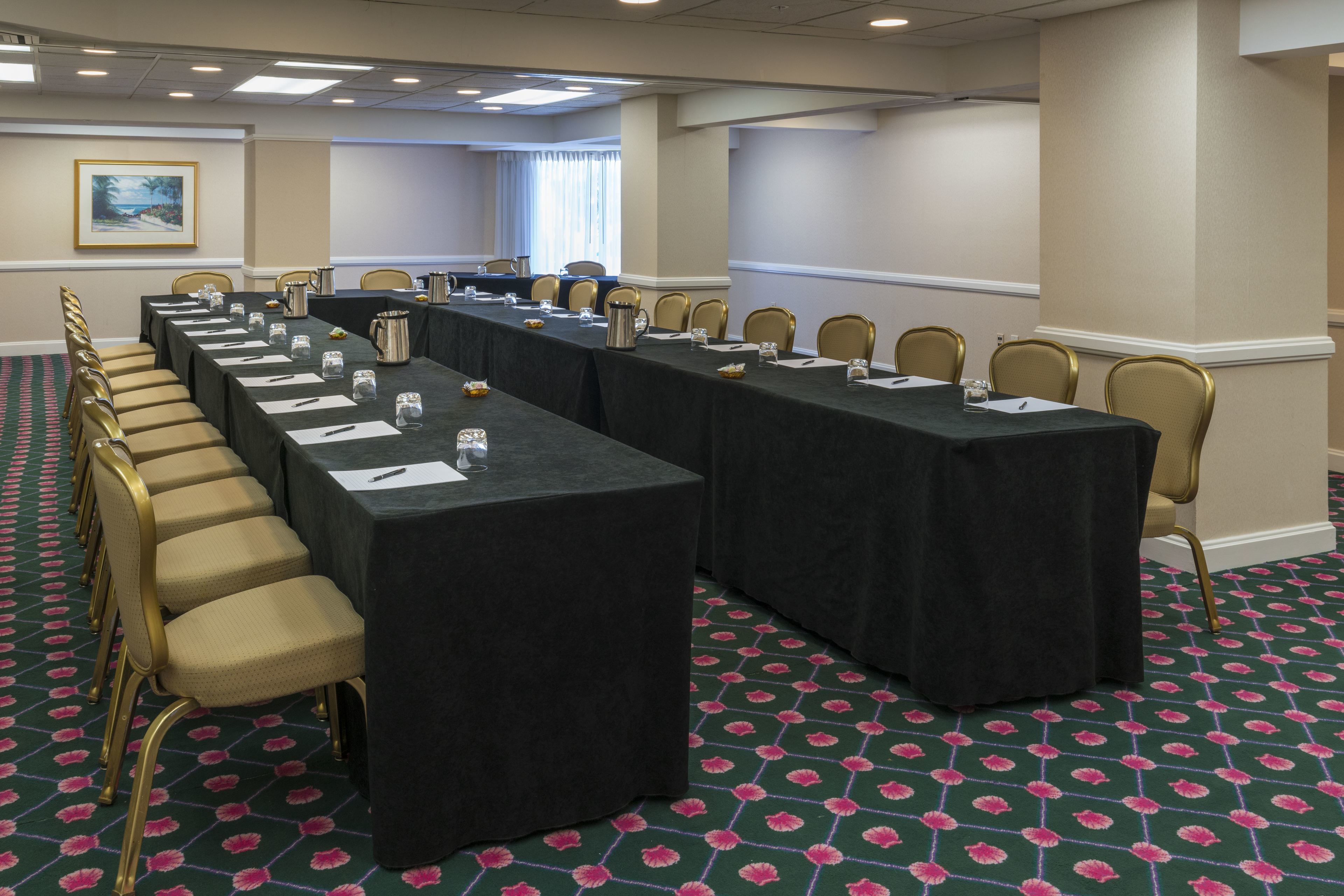 A conference room with a long table, chairs, and a carpeted floor.
