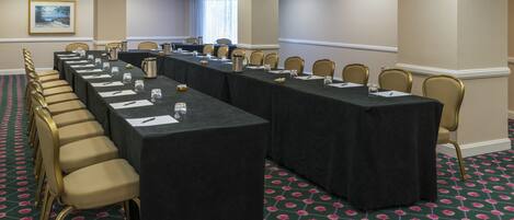 Un salón de conferencias con una mesa larga, sillas y piso alfombrado.