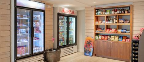 Una tienda limpia y ordenada con secciones refrigeradas, estantes llenos de aperitivos y una gran variedad de bebidas.