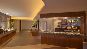A modern hotel lobby with a central reception desk, a seating area, and a view of the outdoors.