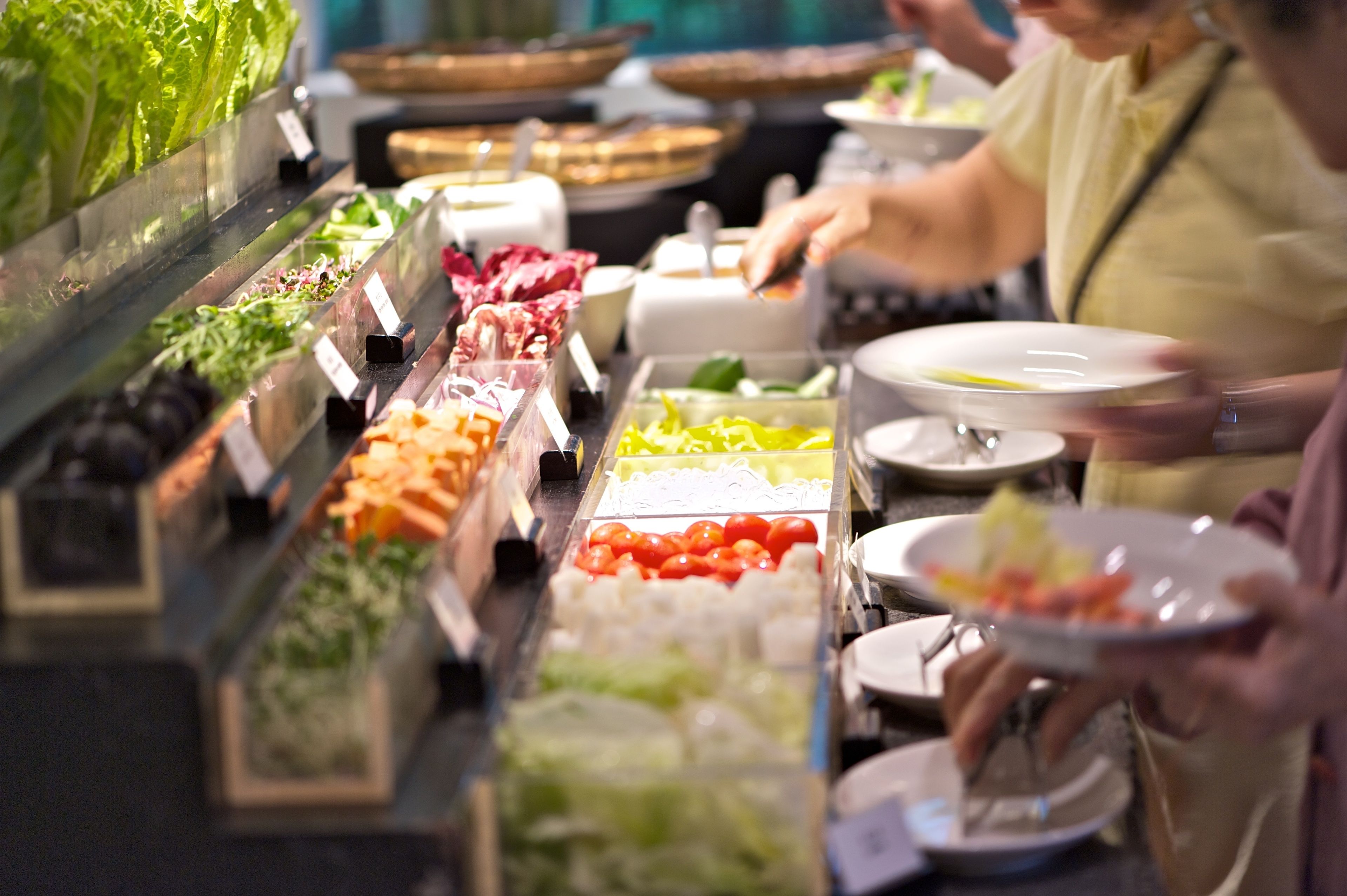 A buffet with various food items and a person serving themselves.