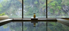 A room with a large window offering a view of a forested cliff. - Silks Place Taroko (Xiulin)