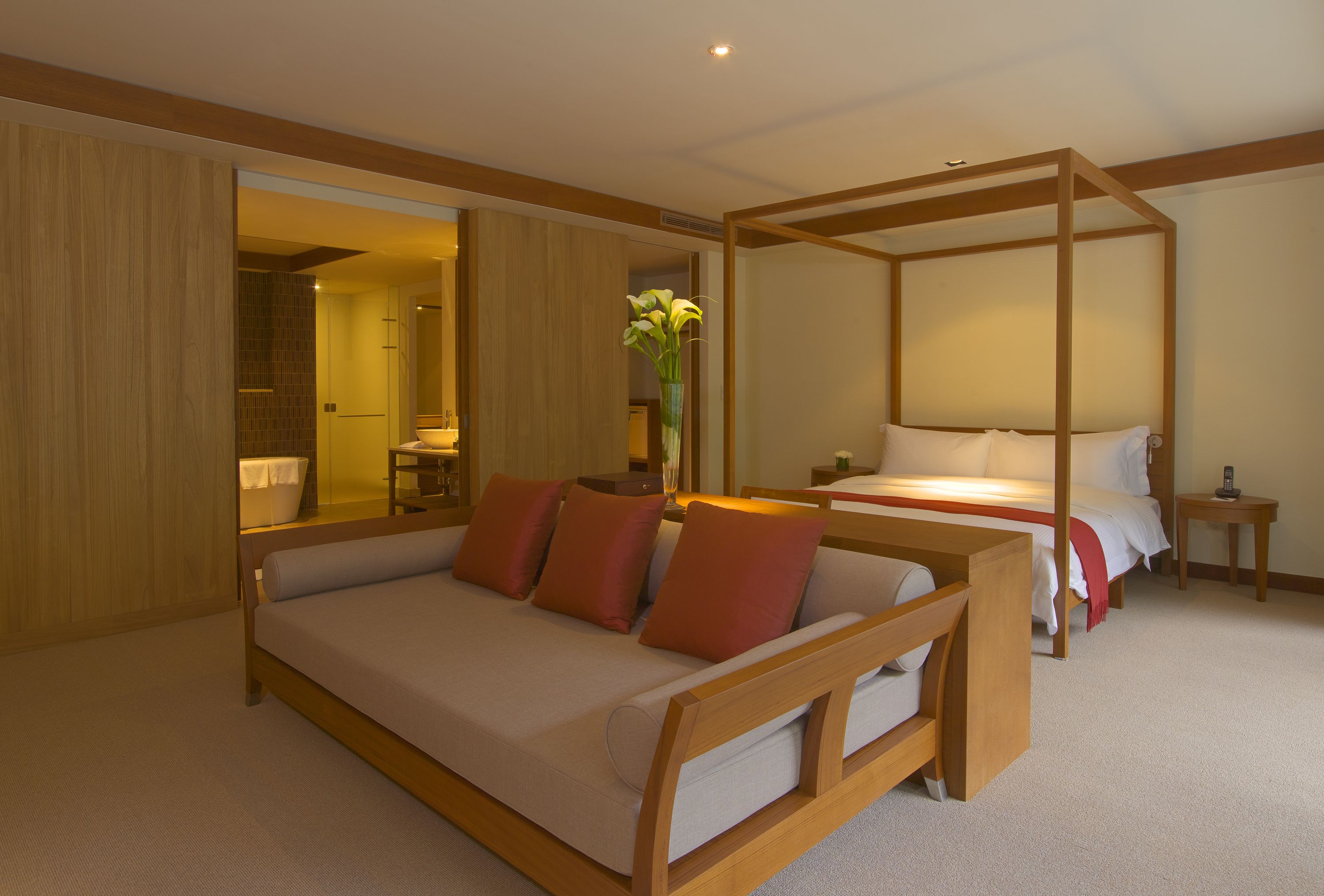 Een moderne hotelkamer met een groot bed, een kleinere bank, een dagbed en een hemelbed.