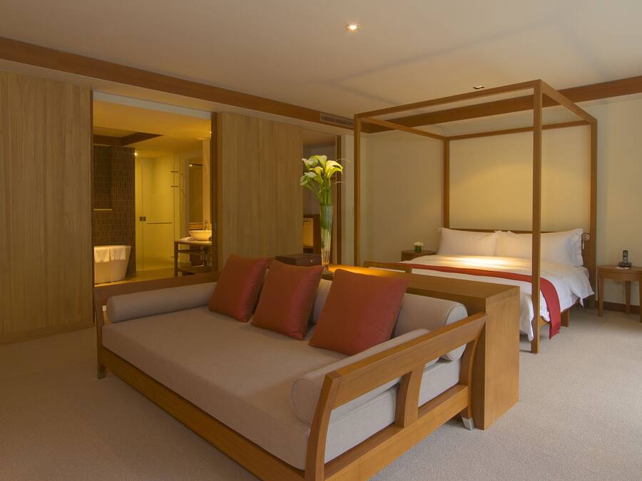 Een moderne hotelkamer met een groot bed, een kleinere bank, een dagbed en een hemelbed.