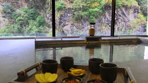 A tray with food and drinks on a table near a window overlooking a rocky landscape. - Silks Place Taroko (Xiulin)