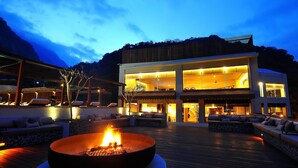 A modern outdoor lounge area with a fire pit, seating, and a view of a contemporary building. - Silks Place Taroko (Xiulin)
