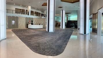 En rummelig lobby med reception, høje lofter og en central søjle.