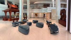 A spacious lobby with modern seating, a traditional wooden structure, and a large horse statue. - Lao Plaza Hotel (Vientiane)