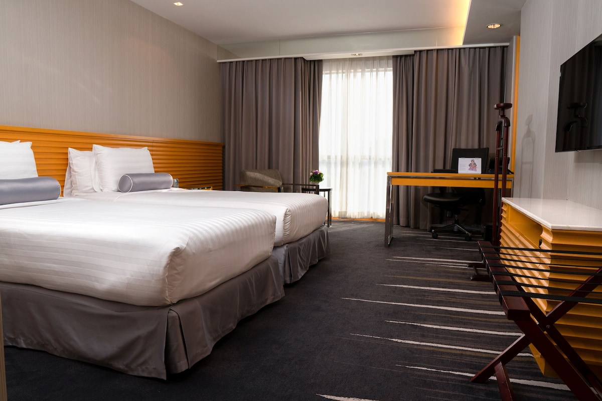 Habitación de hotel con una cama grande, un escritorio, una silla y un televisor.