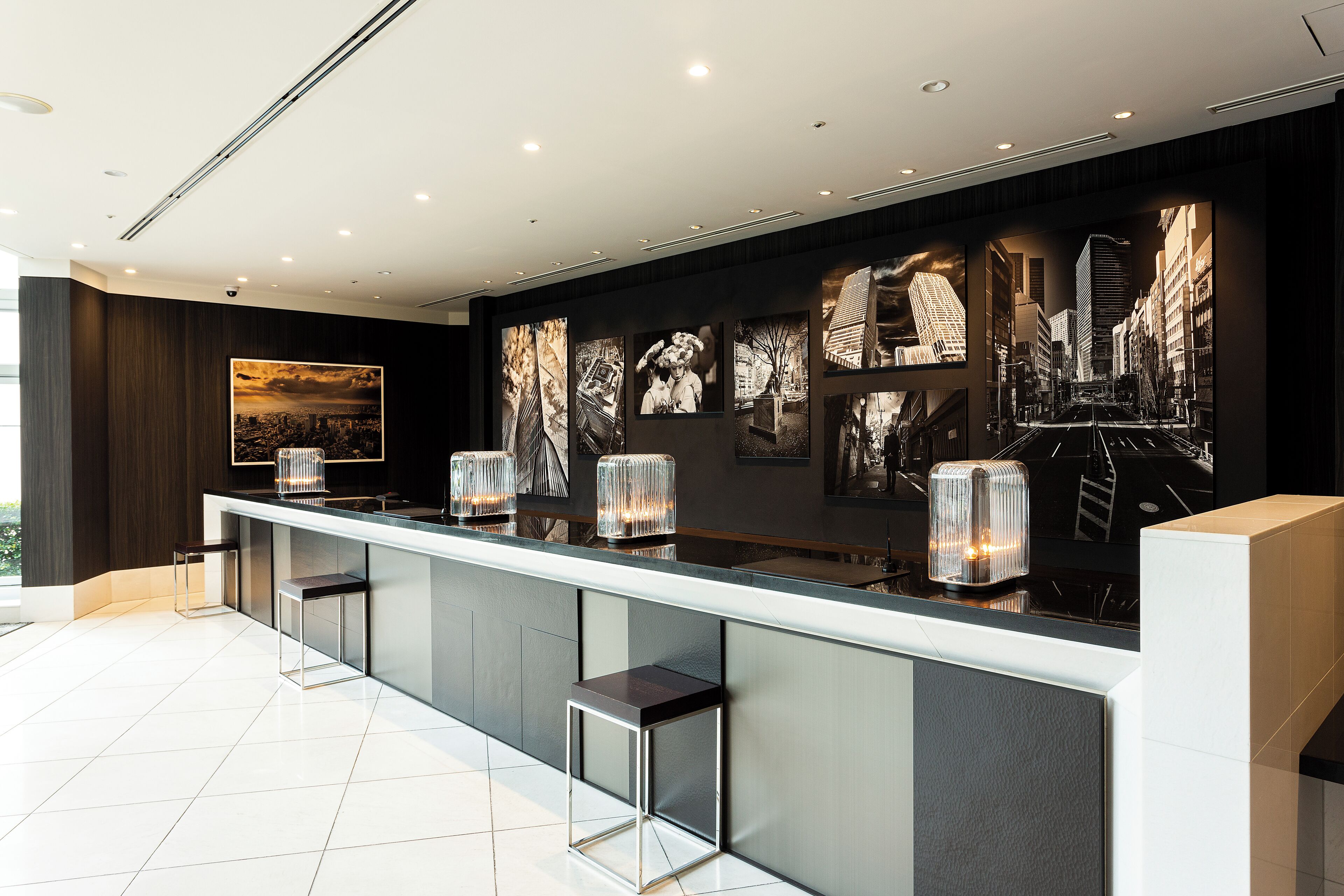 A modern bar area with a long counter, bar stools, and a cityscape mural on the wall.