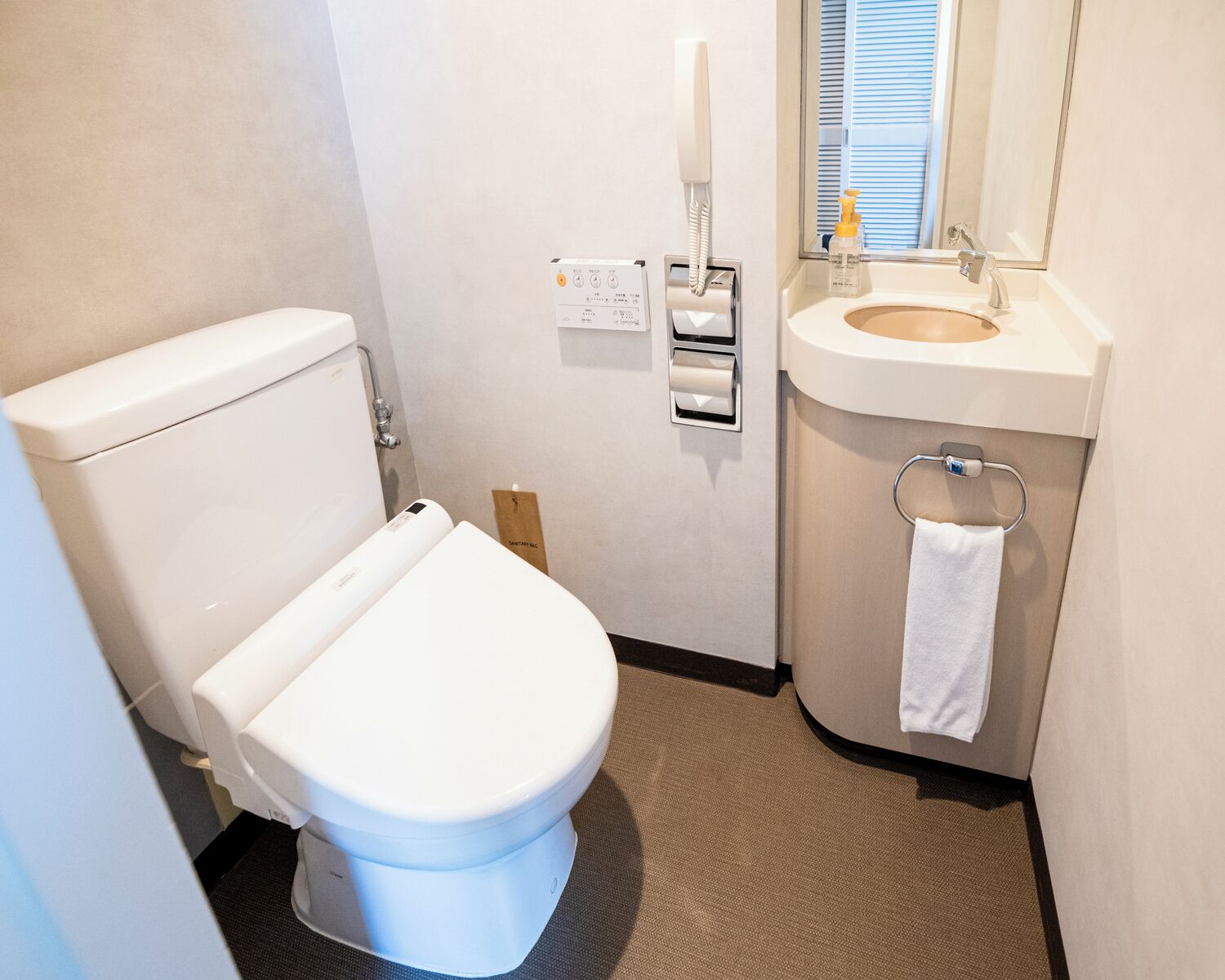 A compact bathroom with a toilet, a sink, and a mirror.