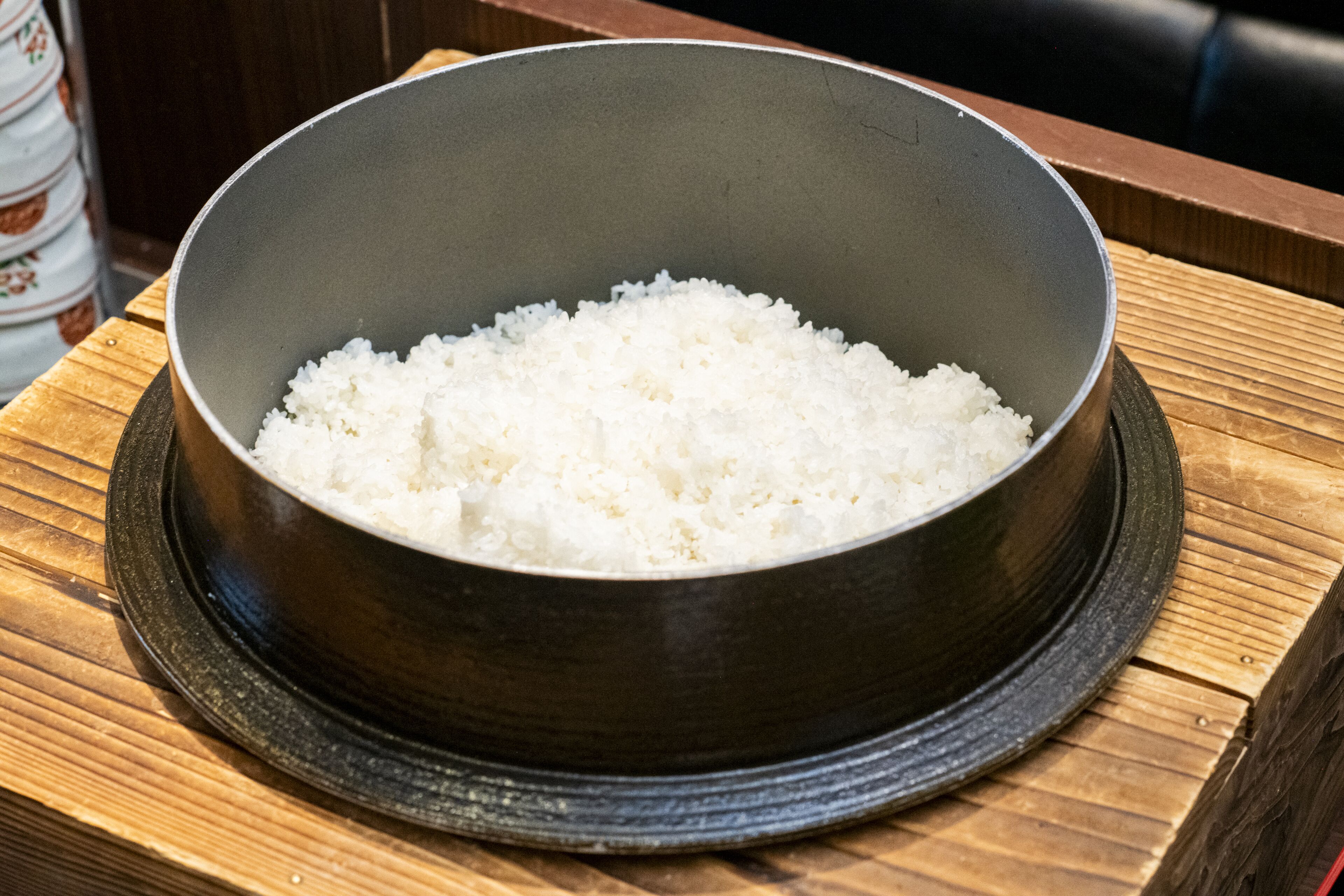 A bowl of white rice on a wooden tray.