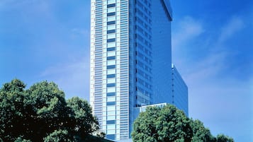 Stunning high-rise building with a unique design, surrounded by lush greenery.