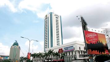 Un edificio de gran altura con un letrero llamativo que dice 'ARMADA' y un cartel publicitario que anuncia Camboya.