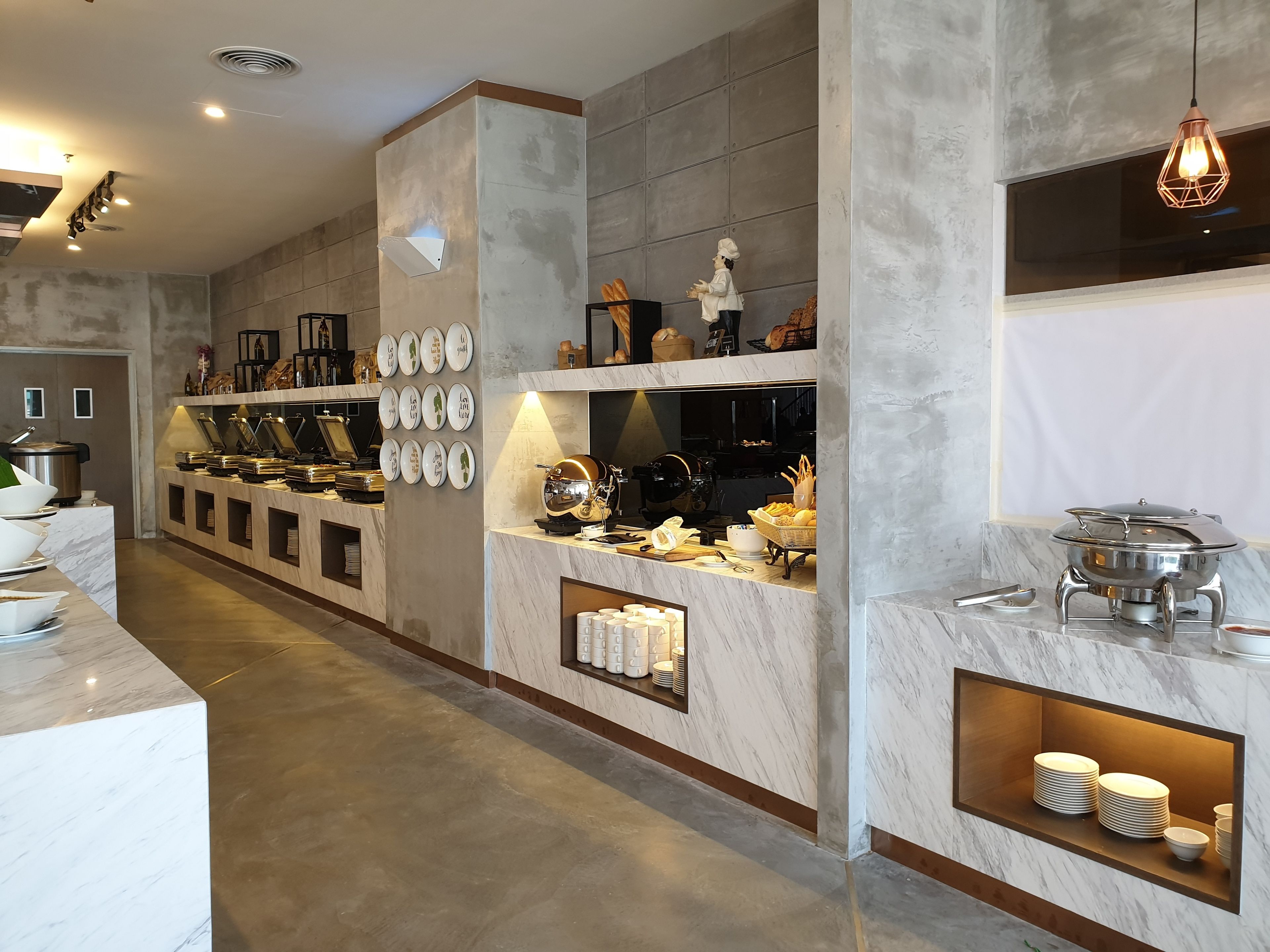 Cocina moderna con encimeras de mármol, cafetera y zona de buffet con platos y cuencos.