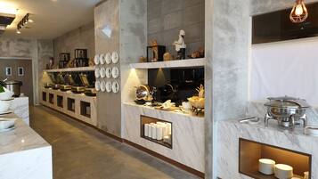 Cocina moderna con encimeras de mármol, cafetera y zona de buffet con platos y cuencos.
